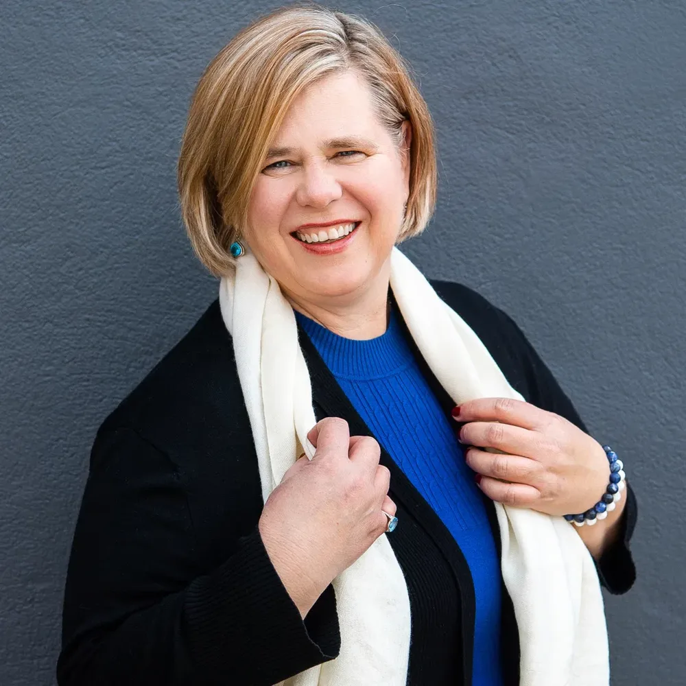 She Crushes Ecom laughing, wearing a blue sweater and cream scarf